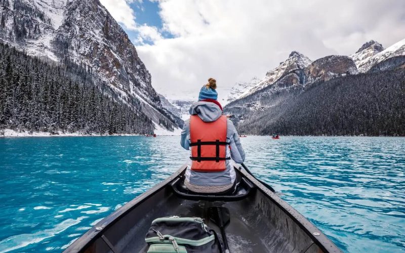 Vue arrière d'une personne portant un gilet de sauvetage dans un canot sur le lac Louise au Canada