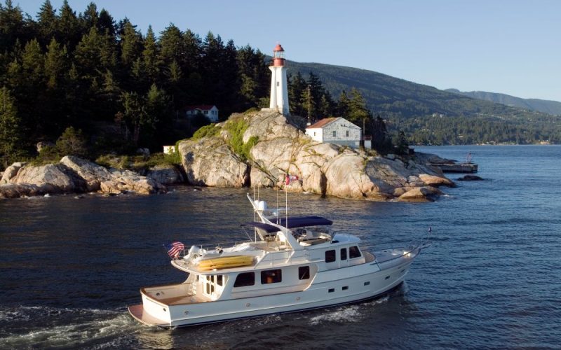 Bateau naviguant près d'un phare sur une côte rocheuse au Canada